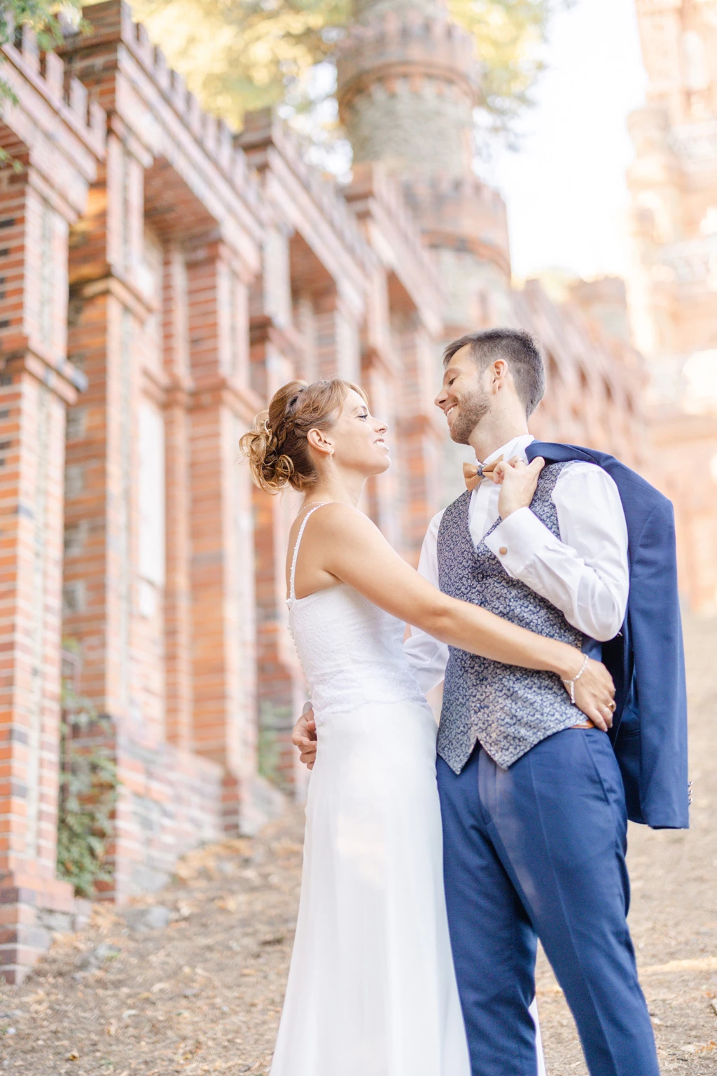 Couple de mariés s'embrassant devant les colonnes d'un château, lumière dorée du soleil couchant