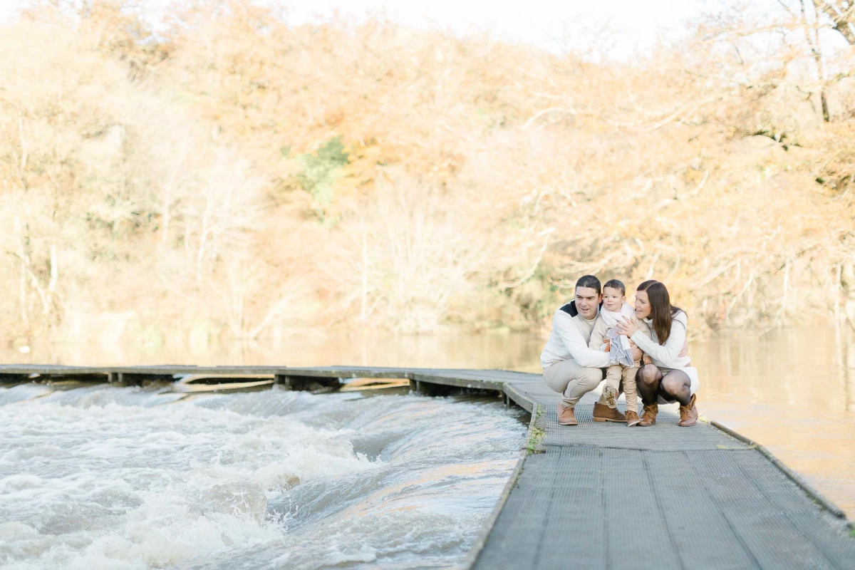Famille heureuse assise sur un ponton au bord d'une rivière dans une atmosphère automnale dorée