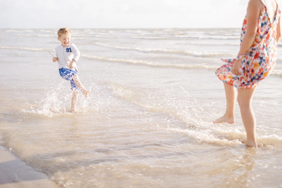 Mère et fils jouant dans les vagues au bord de la mer, moment de complicité estivale