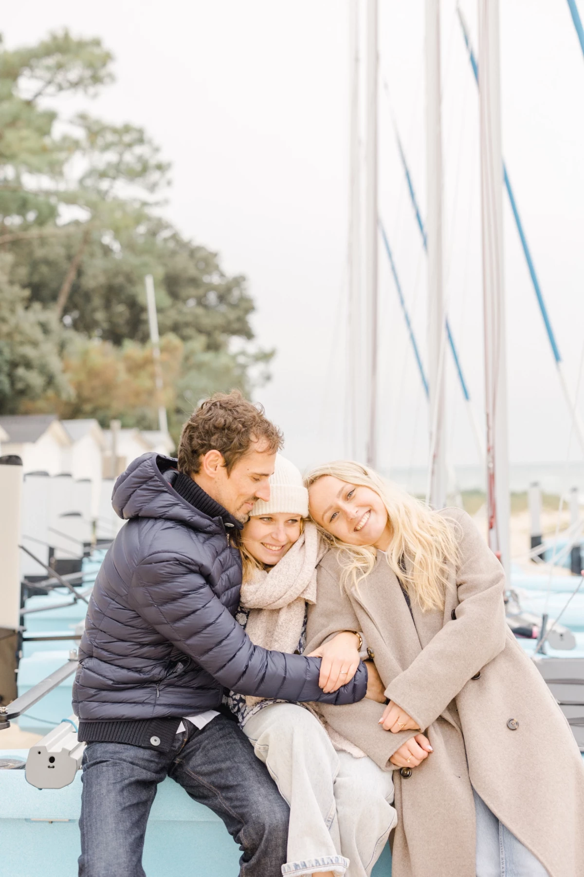Famille complice enlacée sur un ponton de marina, parents et enfant blottis ensemble