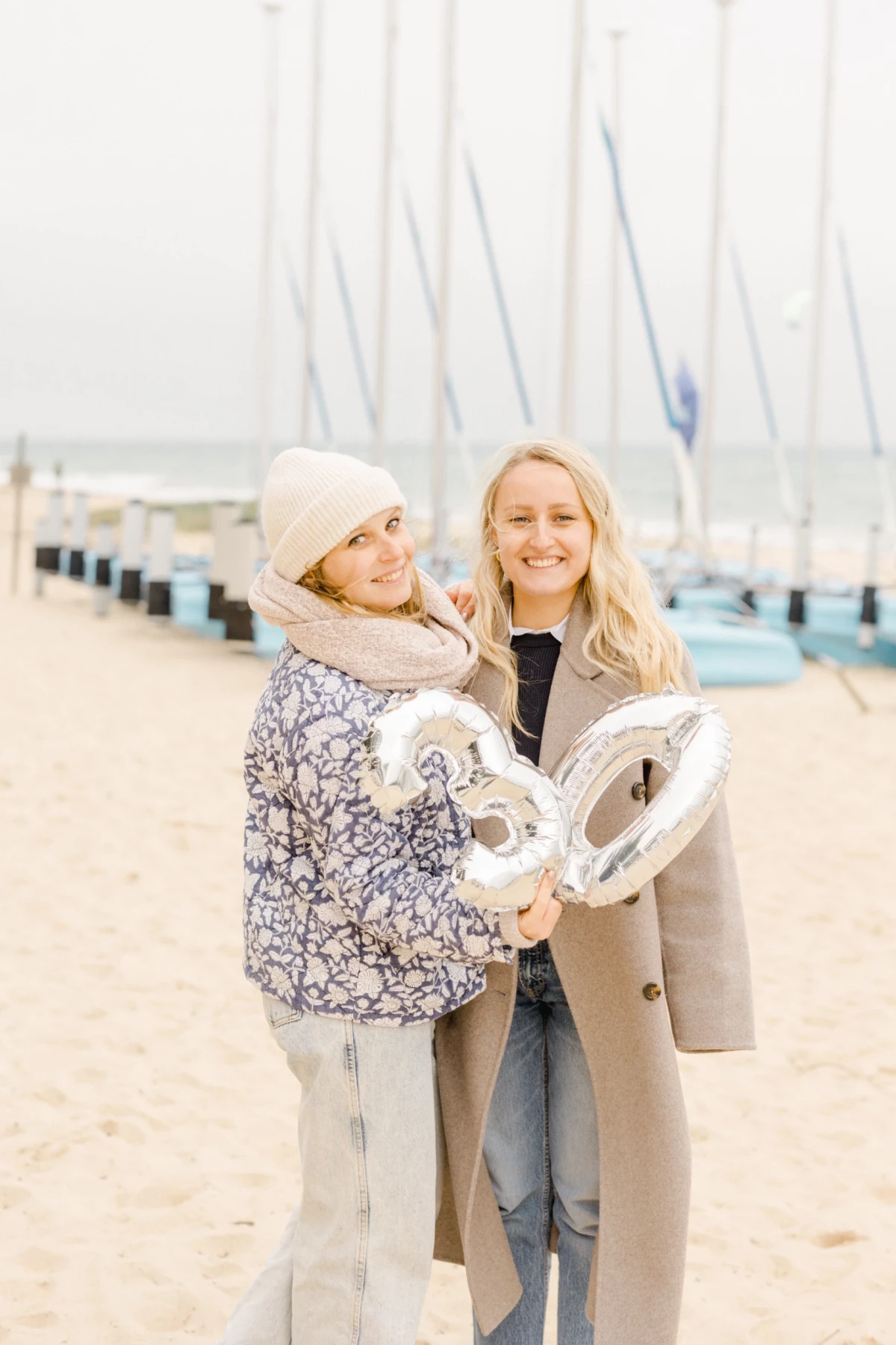 Mère et fille enlacées sur une plage, souriant à l'appareil avec un ballon blanc en forme de cœur