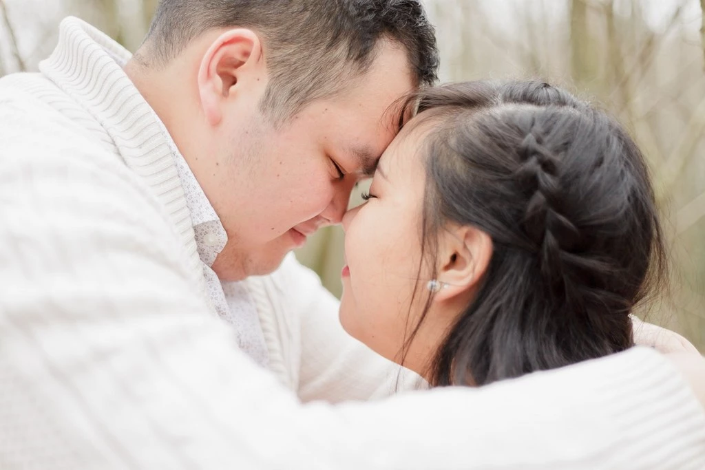 Couple enlacé partageant un moment de tendresse en extérieur, front contre front dans une lumière douce