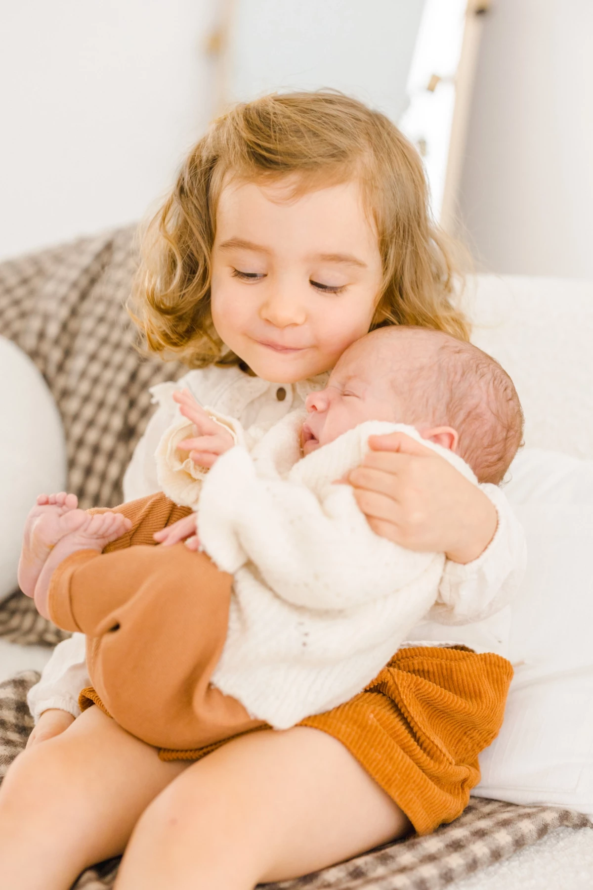 Grande sœur tenant tendrement son nouveau-né dans les bras, moment de complicité familiale