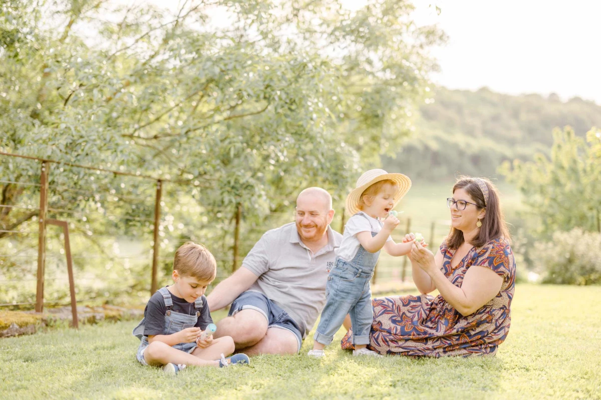 Famille multigénérationnelle réunie dans un pré verdoyant, grands-parents et petits-enfants partageant un moment joyeux