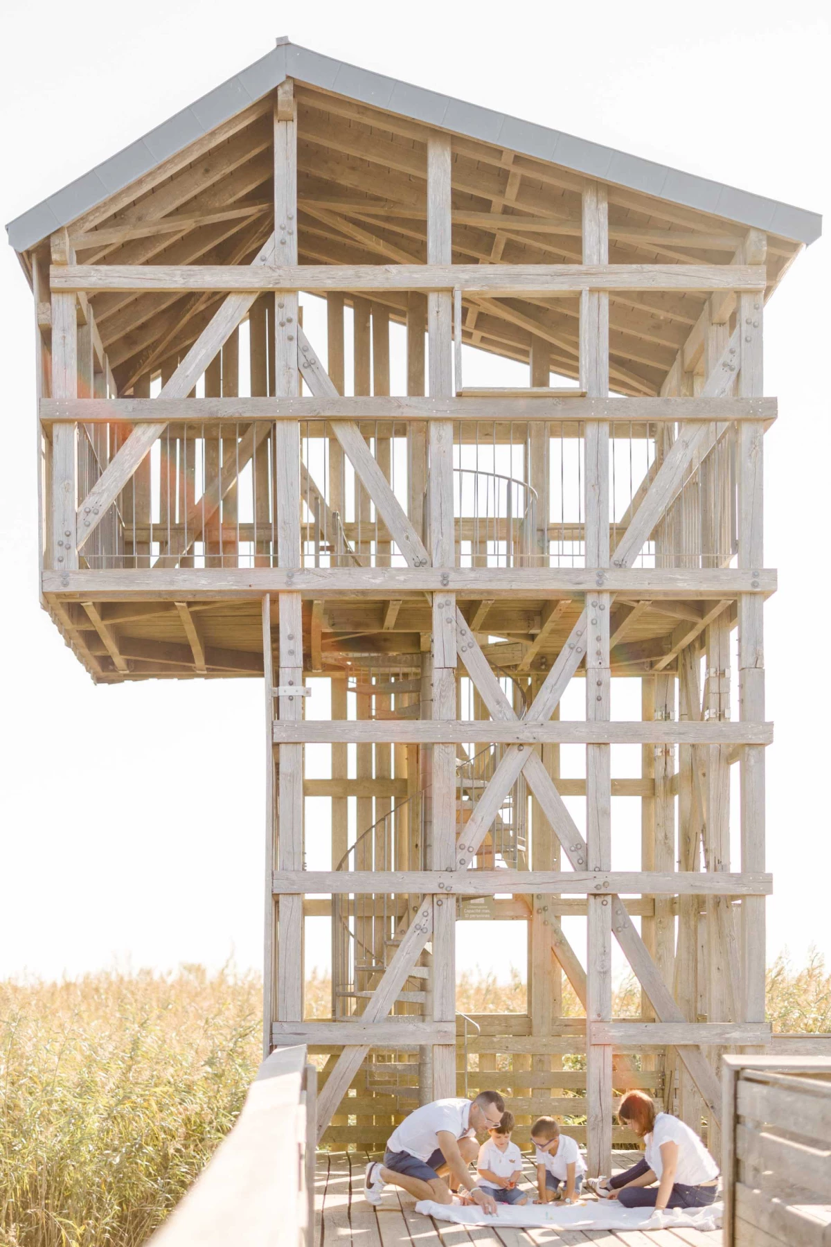 Famille jouant ensemble sur une terrasse en bois sous une structure architecturale moderne à colombages