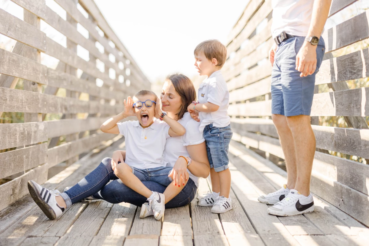 Famille avec deux jeunes garçons posant sur un ponton en bois au coucher du soleil