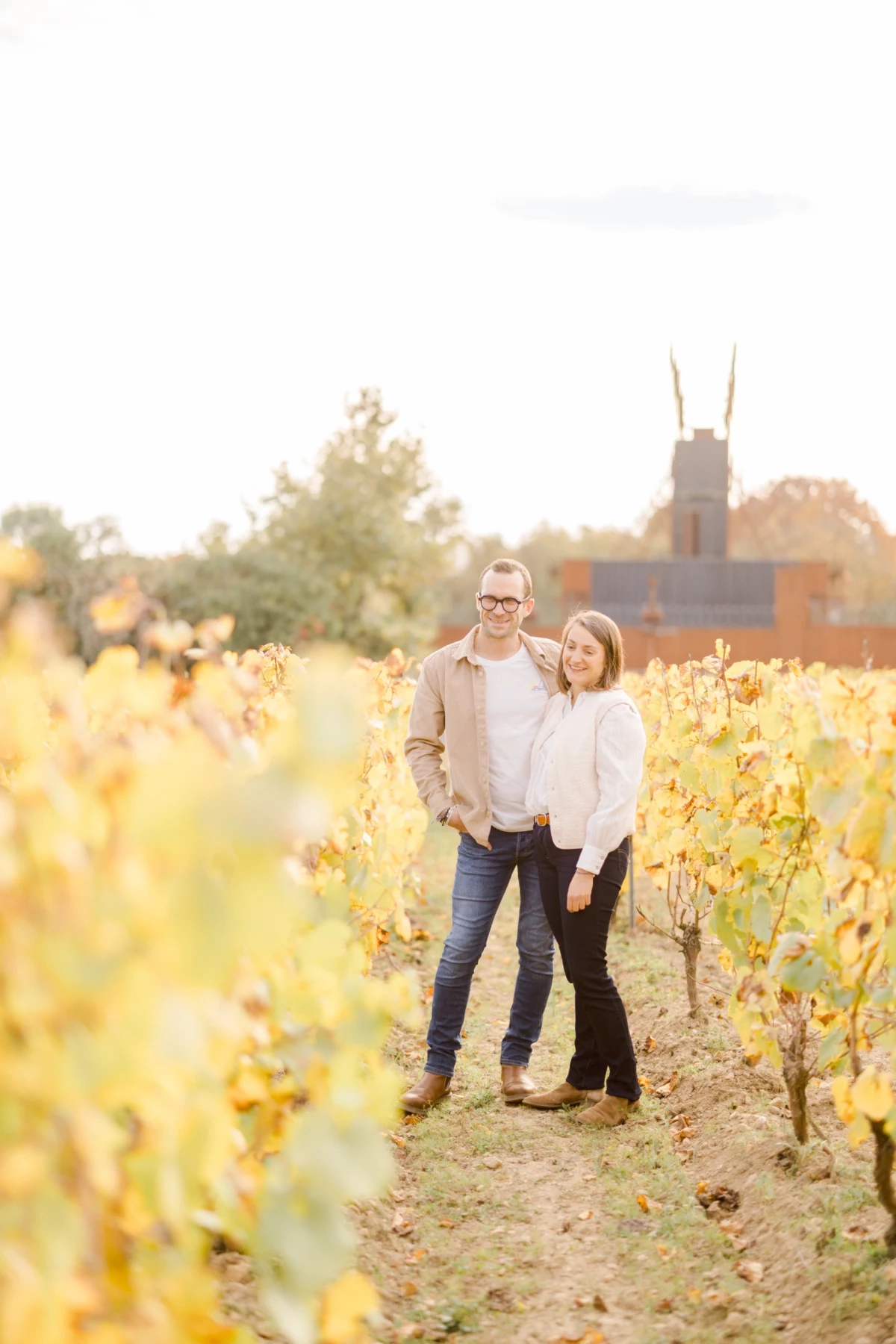 Couple complice dans un vignoble aux couleurs automnales sous une lumière dorée et douce
