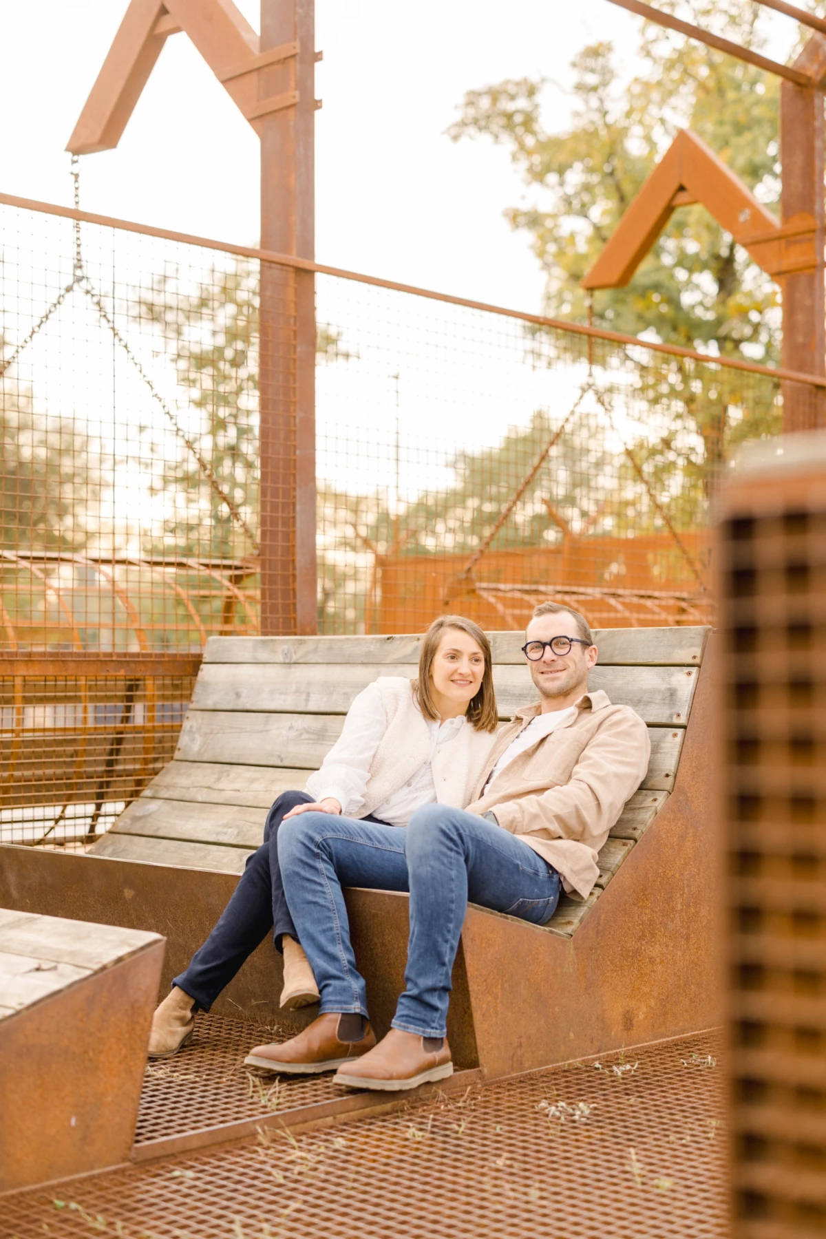 Couple complice assis sur un banc en bois dans un parc urbain à la lumière dorée du coucher de soleil