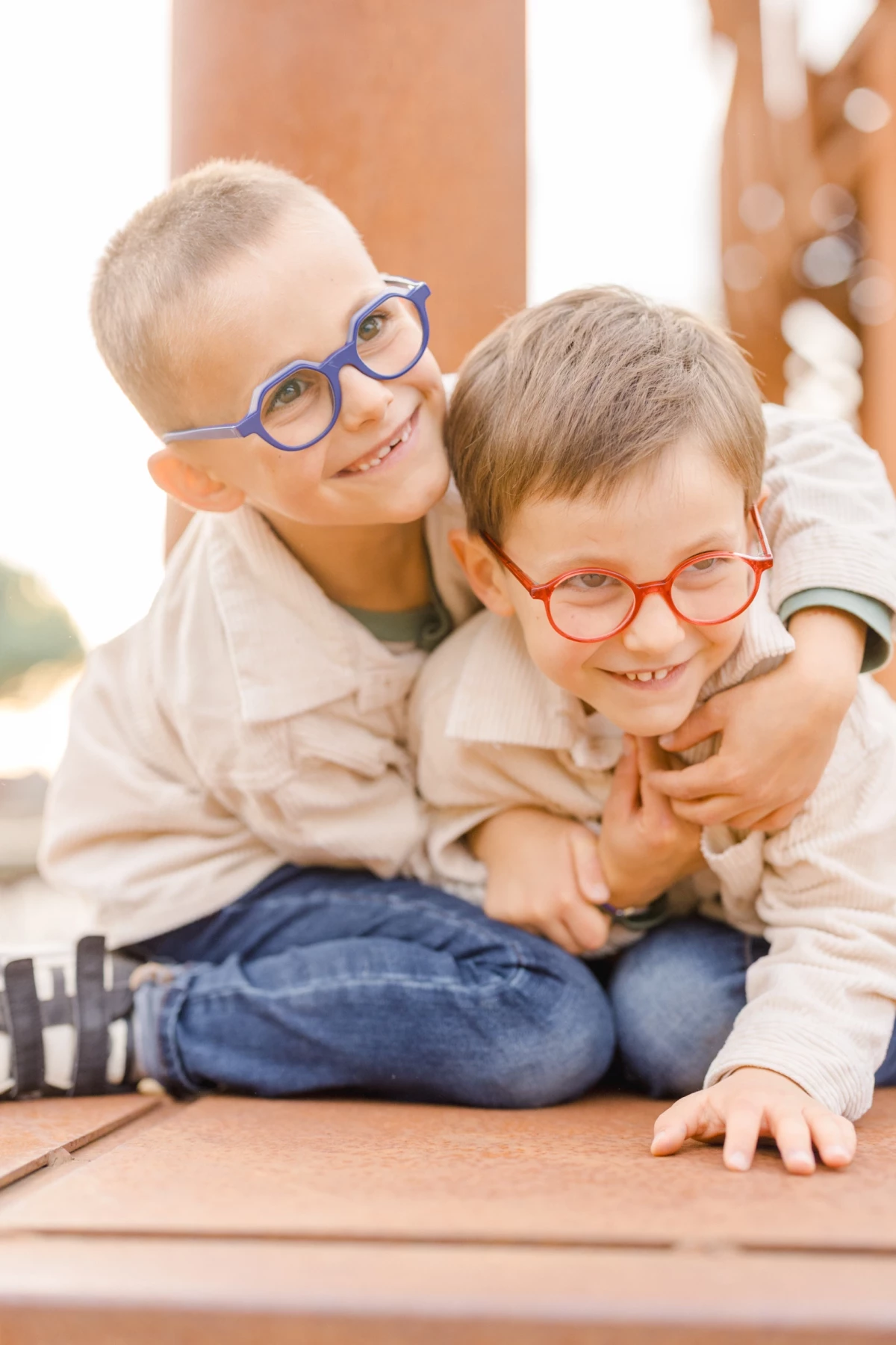 Deux jeunes frères complices portant des lunettes colorées sourient à la caméra lors d'une séance photo en studio