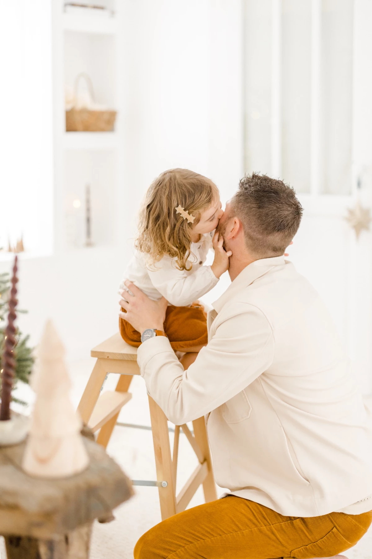 Père en chemise blanche partageant un tendre câlin avec sa fille en intérieur lumineux