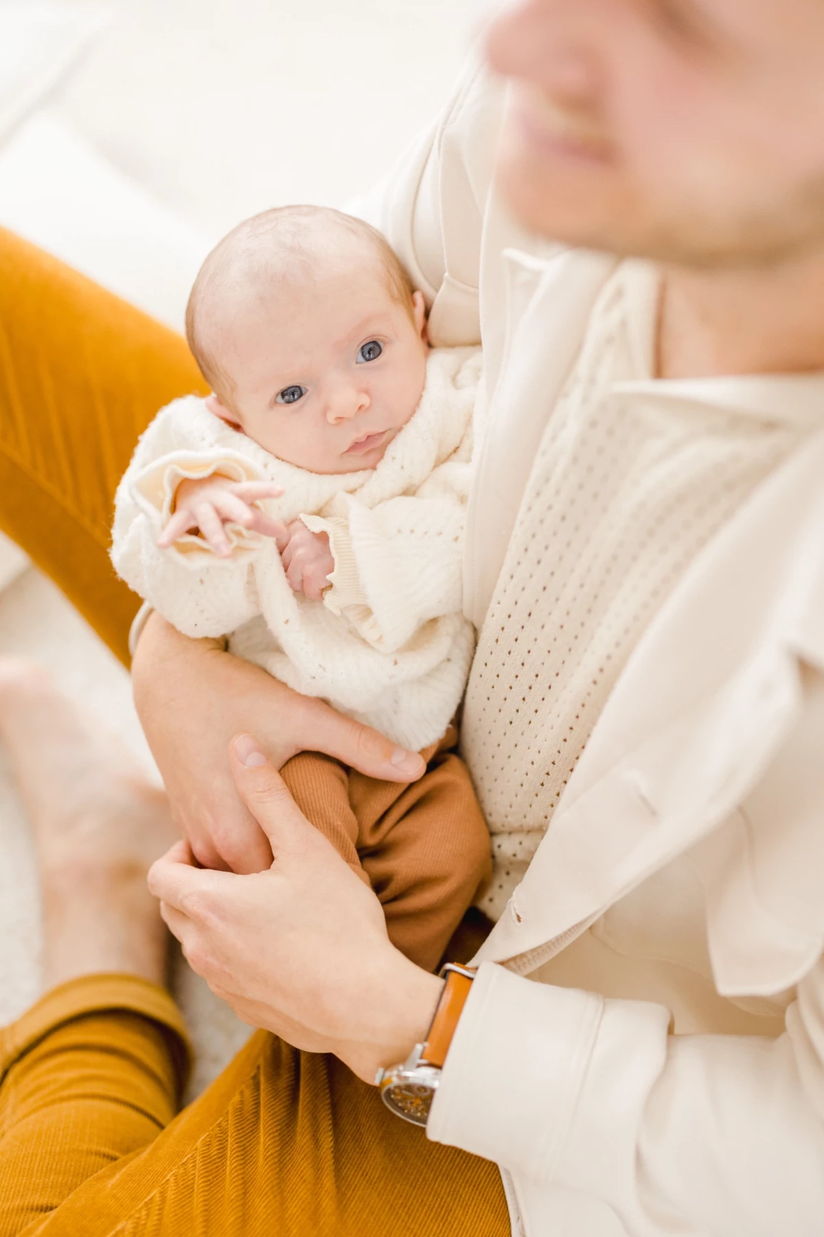 Mère tenant tendrement son nouveau-né en tenue beige et blanche, capturant un moment de douceur familiale