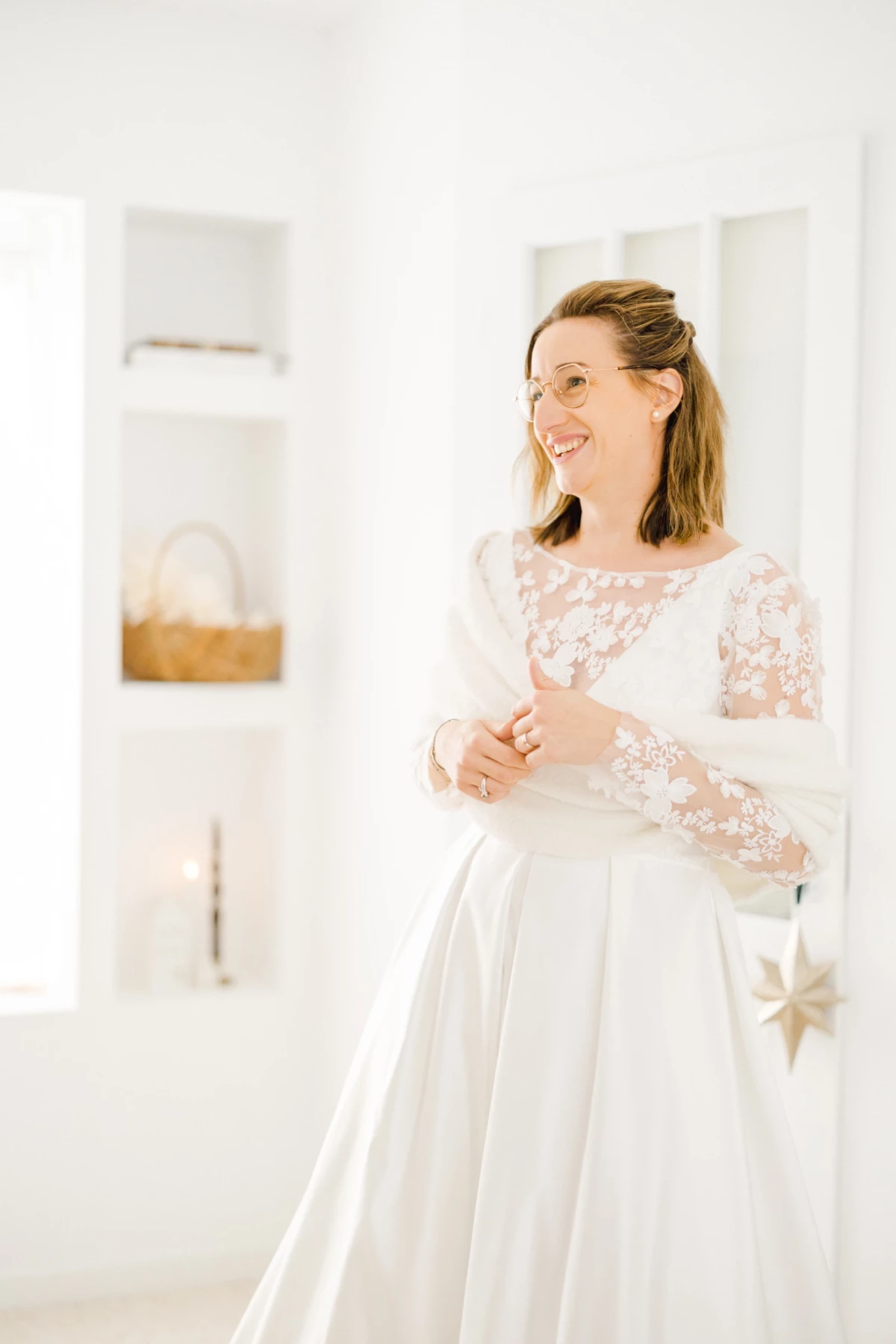 Mariée souriante en robe de mariée blanche à manches en dentelle florale lors de ses préparatifs