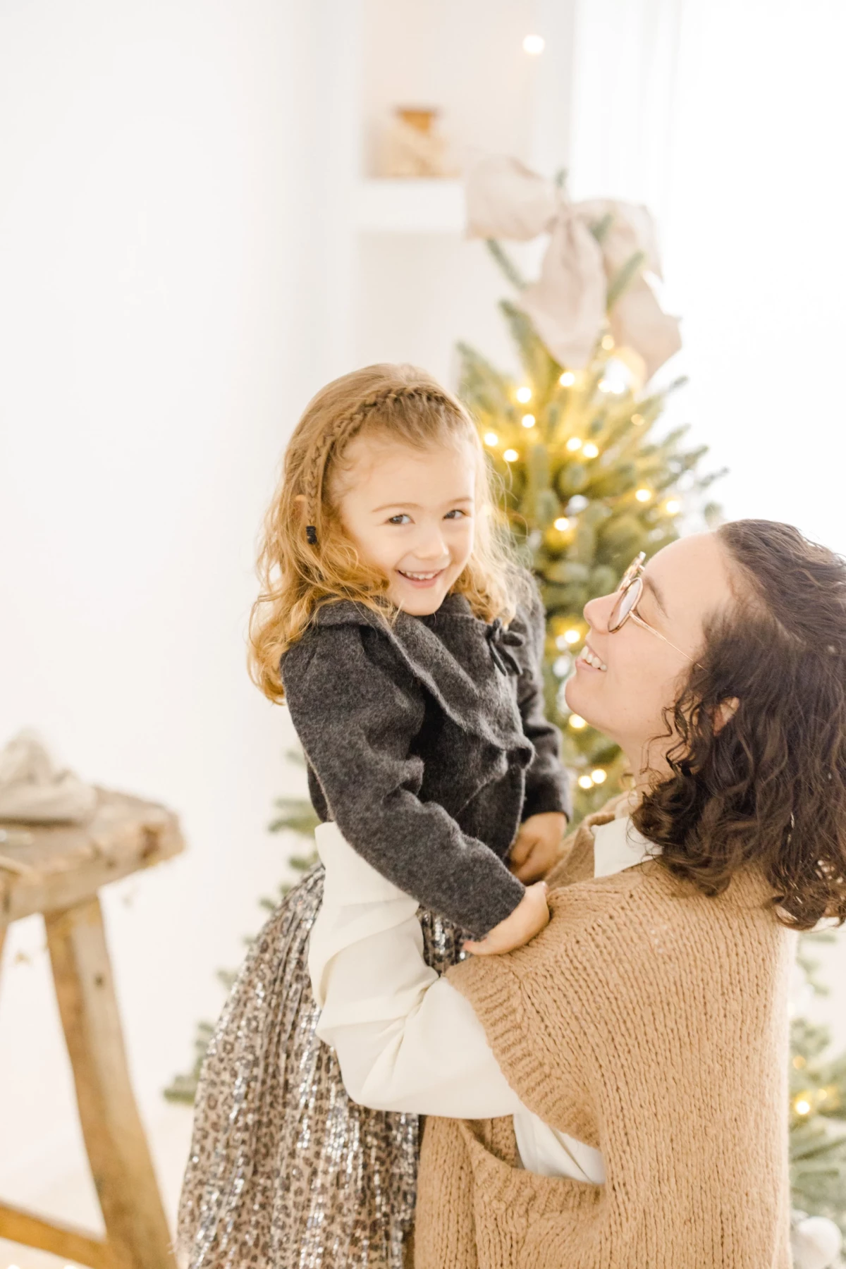Mère et fille partageant un moment complice devant un sapin de Noël illuminé