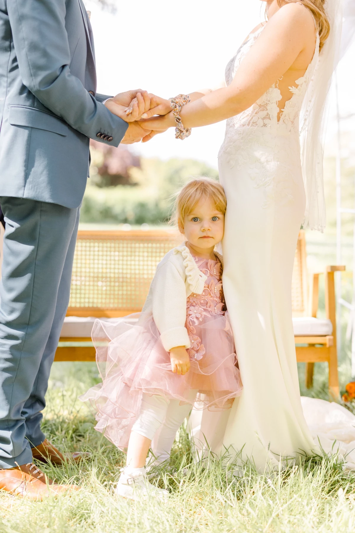 Jeune fille en robe rose au premier plan lors d'une cérémonie de mariage en extérieur sur l'herbe