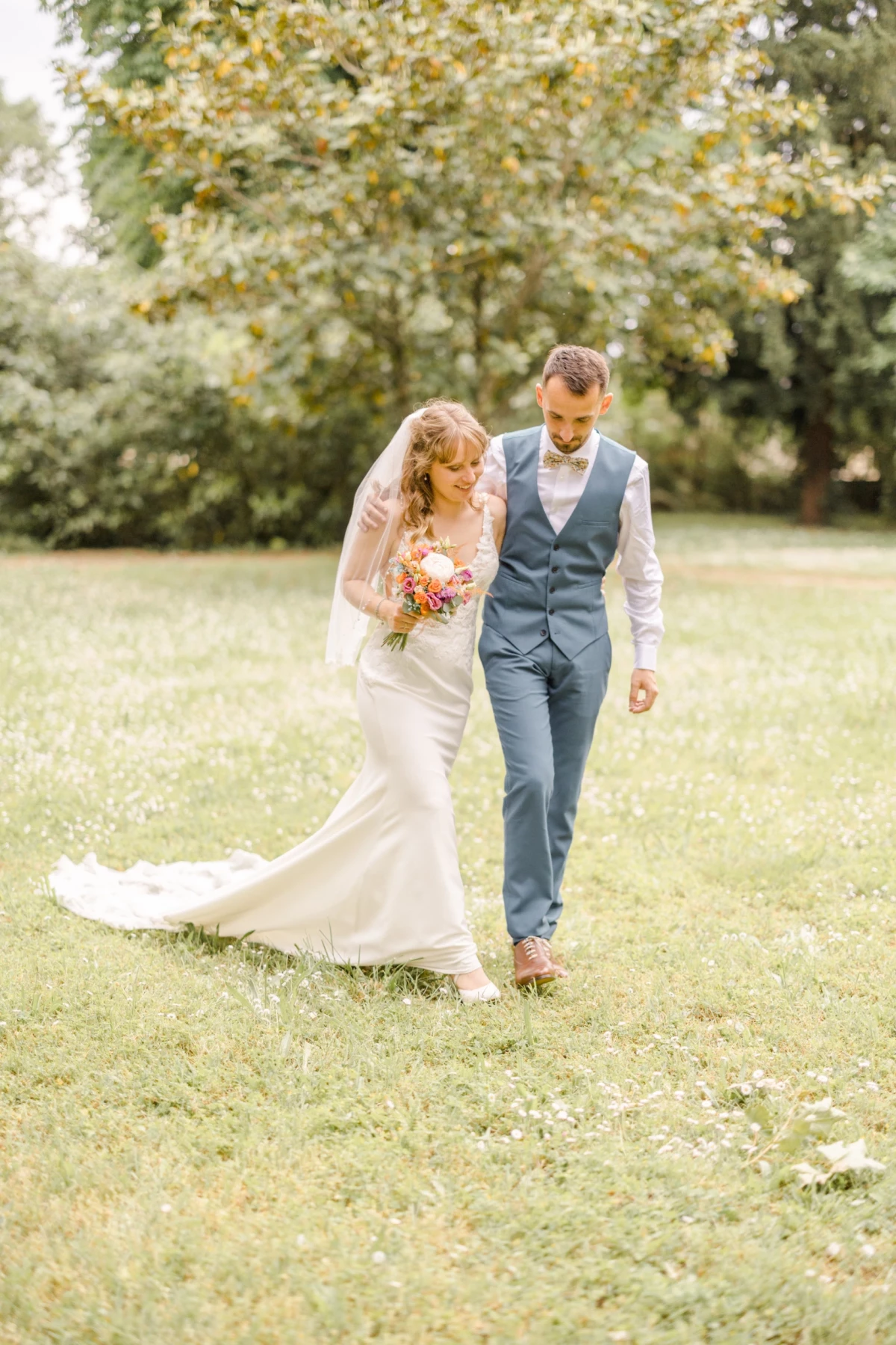 Couple de mariés marchant main dans la main sur une pelouse verdoyante lors de leur cérémonie champêtre