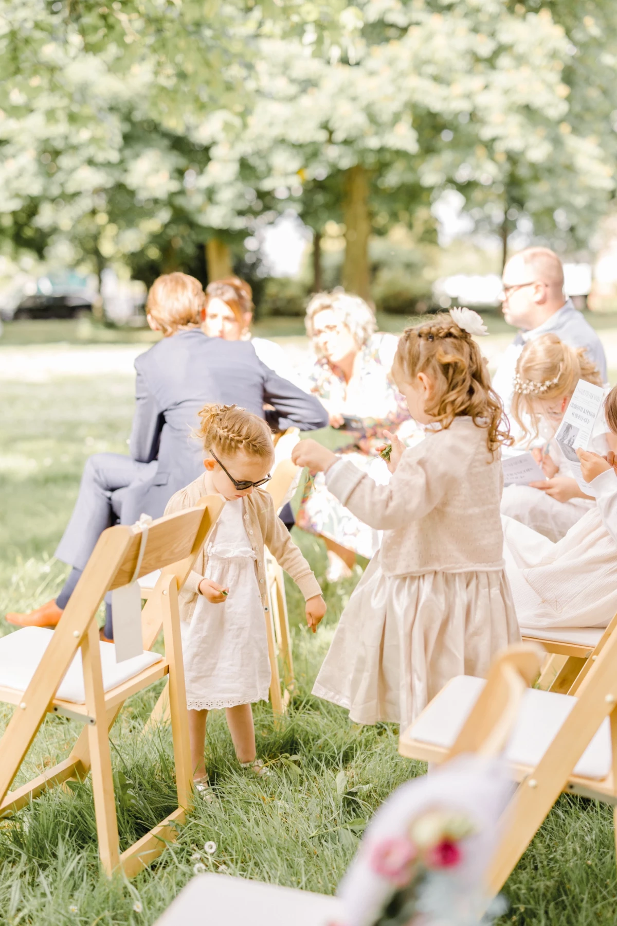 Deux petites filles en robes blanches jouent pendant une cérémonie de mariage en plein air