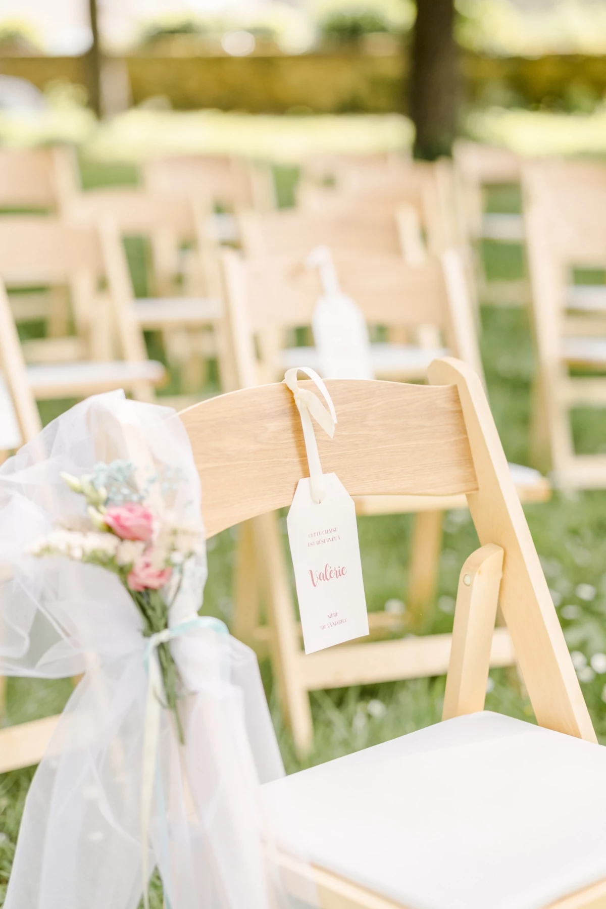 Chaises blanches décorées de voile et fleurs pour cérémonie de mariage en extérieur