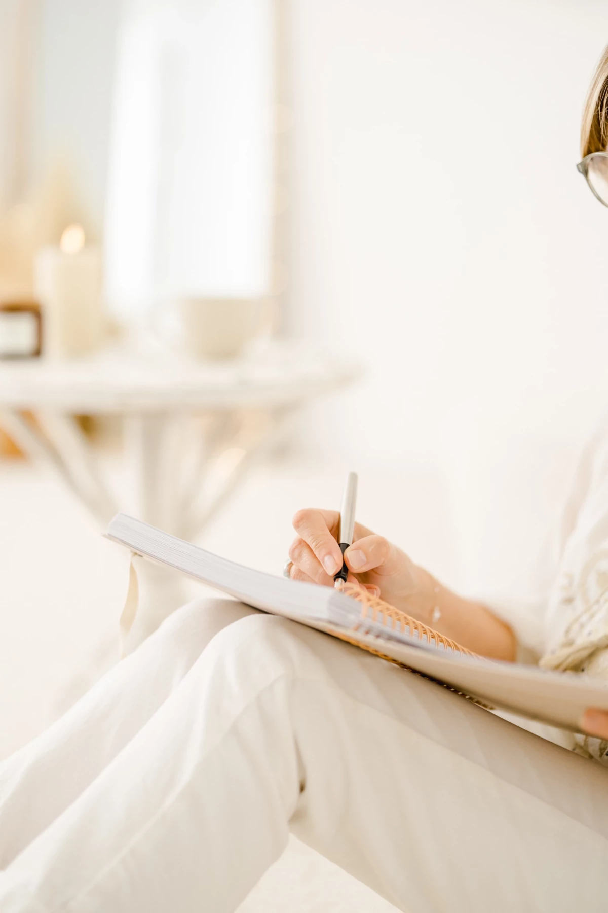 Future mariée écrivant ses vœux sur un carnet lors des préparatifs de mariage en robe blanche